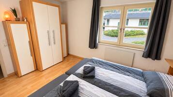 Une chambre à coucher avec un lit, une armoire, une fenêtre avec des rideaux et une vue sur l’extérieur.