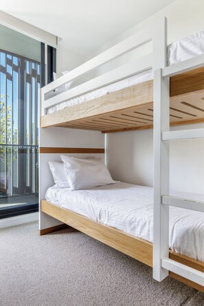 A bunk bed with white bedding and wooden headboard in a room with a large window. - Vyra at Arden Park Minutes to Dining Shops and CBD (North Melbourne)