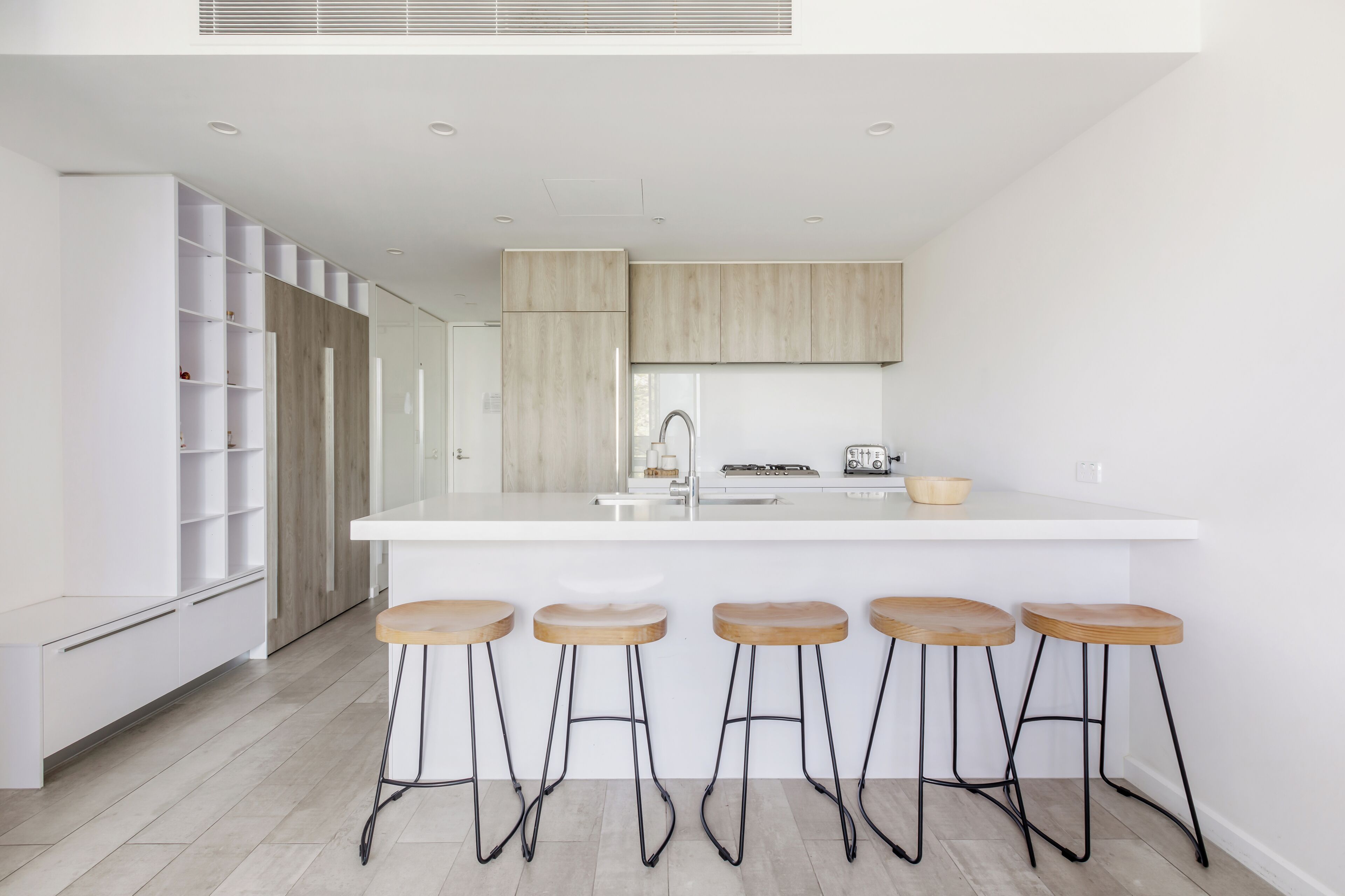 A modern kitchen with a central island, bar stools, and built-in cabinetry.
