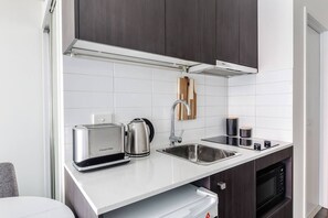 Eine moderne Küche mit weißen Arbeitsplatten, Edelstahlgeräten und dunklen Holzschränken.