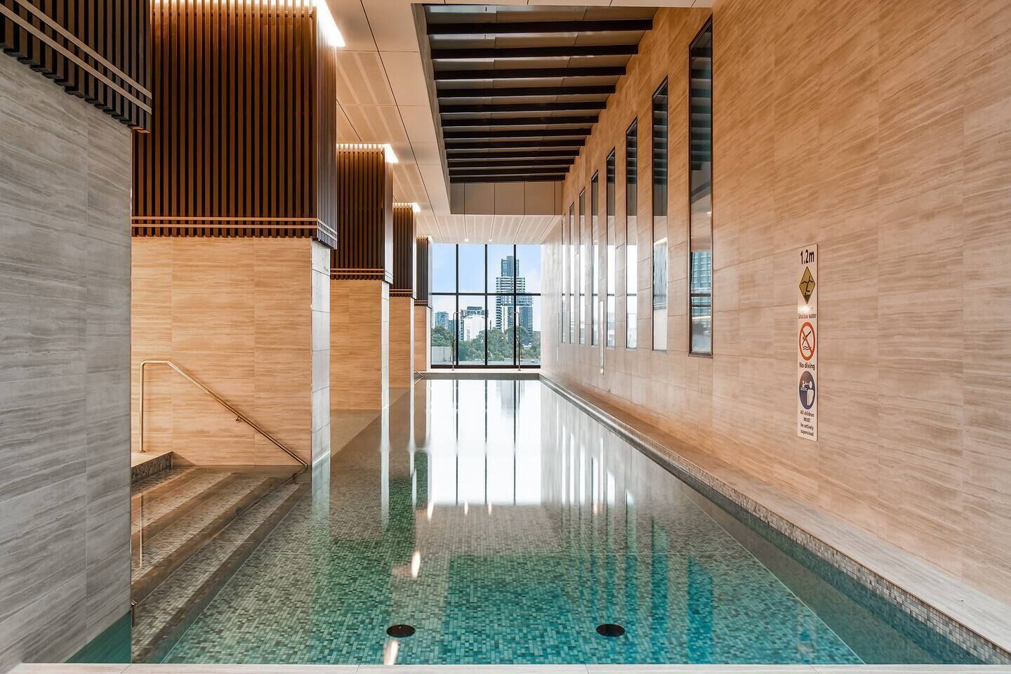 Ein moderner, überdachter Pool mit freiem Blick auf die Stadt durch große Fenster.