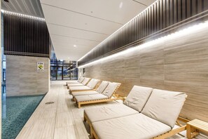 Ein moderner Wellnessbereich mit Holzliegen, einem Warnschild und Blick ins Freie.