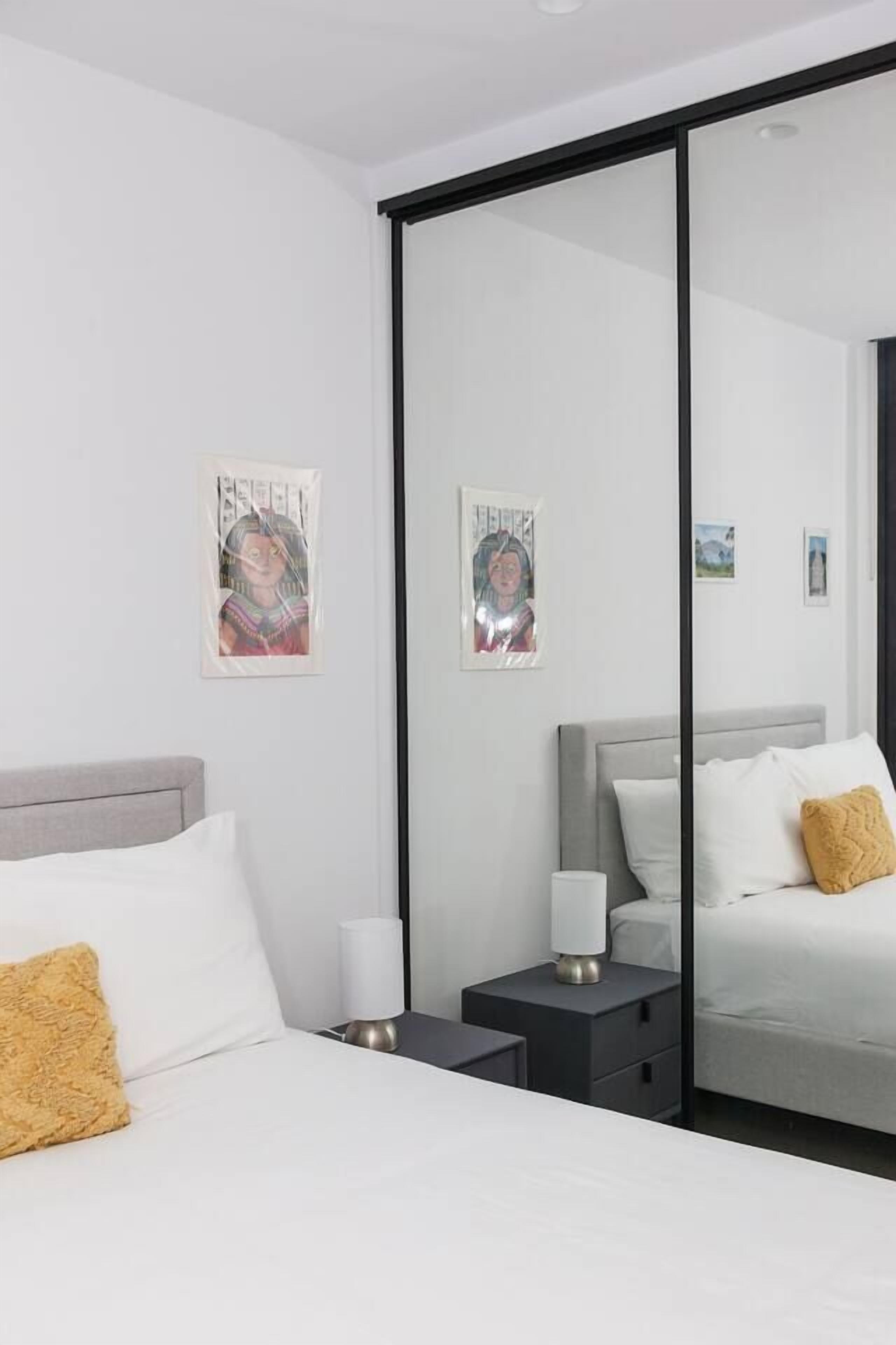 A modern hotel room with a bed, bedside tables, a nightstand, and wall art.