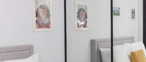 Une chambre d’hôtel moderne équipée d’un lit, de tables de chevet, d’une petite table et d’œuvres d’art murales.