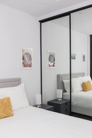 Een moderne hotelkamer met een bed, nachtkastjes, een nachtlampje en wanddecoratie.
