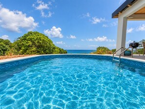 A clear blue swimming pool with a view of the ocean and lush greenery in the background. - Sunset Sea-Clusion | Private Pool & Ocean Views (Frederiksted)