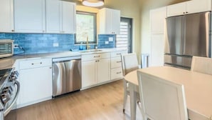 A kitchen with white cabinets, stainless steel appliances, a ceiling fan, and a window. - Sunset Sea-Clusion | Private Pool & Ocean Views (Frederiksted)