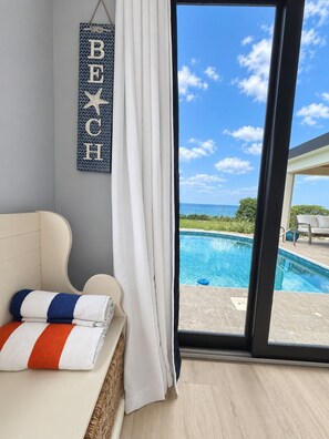 Una habitación con vista a una piscina, un letrero colgante con la palabra 'BEACH' y un juego de toallas.
