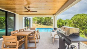 An outdoor patio with a pool, a dining table with chairs, a grill, and a ceiling fan. - Sunset Sea-Clusion | Private Pool & Ocean Views (Frederiksted)