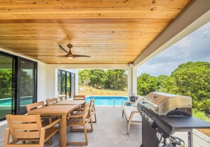 An outdoor patio with a pool, a dining table with chairs, a grill, and a ceiling fan. - Sunset Sea-Clusion | Private Pool & Ocean Views (Frederiksted)