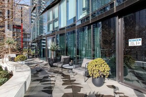 A modern building with large glass windows, outdoor seating area with chairs and a table, and a sign indicating the door is closed. - Skyline 40 Southbank Made Easy with Pool and Gym (Southbank)