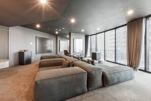 A modern living room with a large sectional sofa, a flat-screen TV, and a large window with a city view. - Skyline 40 Southbank Made Easy with Pool and Gym (Southbank)