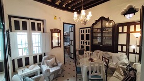 A room with a chandelier, a dining table, a sofa, and a chair.
