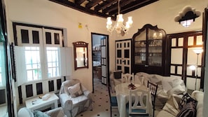 Una habitación con una araña, una mesa de comedor, un sofá y una silla.