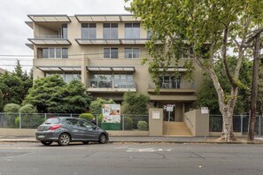 A multi-story residential building with balconies, a car parked in front, and a no parking sign. - Experience the St Kilda Vibe from a Cosy Retreat (Saint Kilda)