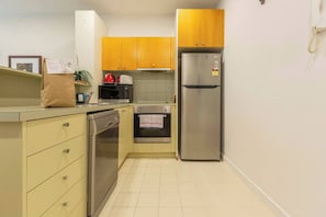 A compact kitchen with a dishwasher, microwave, oven, and refrigerator. - Experience the St Kilda Vibe from a Cosy Retreat (Saint Kilda)