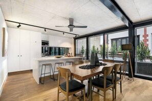 Une cuisine moderne avec des meubles blancs, un îlot central et des tabourets de bar.