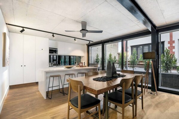 Een moderne keuken met witte kastjes, een centraal eiland en barstoelen.