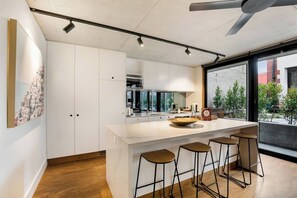 Een moderne keuken met een groot kookeiland, barstoelen en uitzicht op de omgeving.