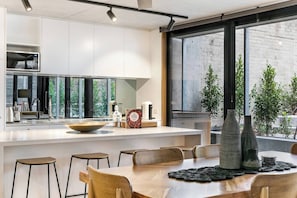 Een moderne keuken met een groot eiland, barkrukken en een eettafel met een placemat.