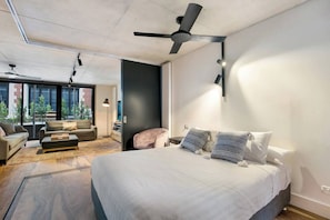Een moderne hotelkamer met een groot bed, een plafondventilator en uitzicht op de omgeving.