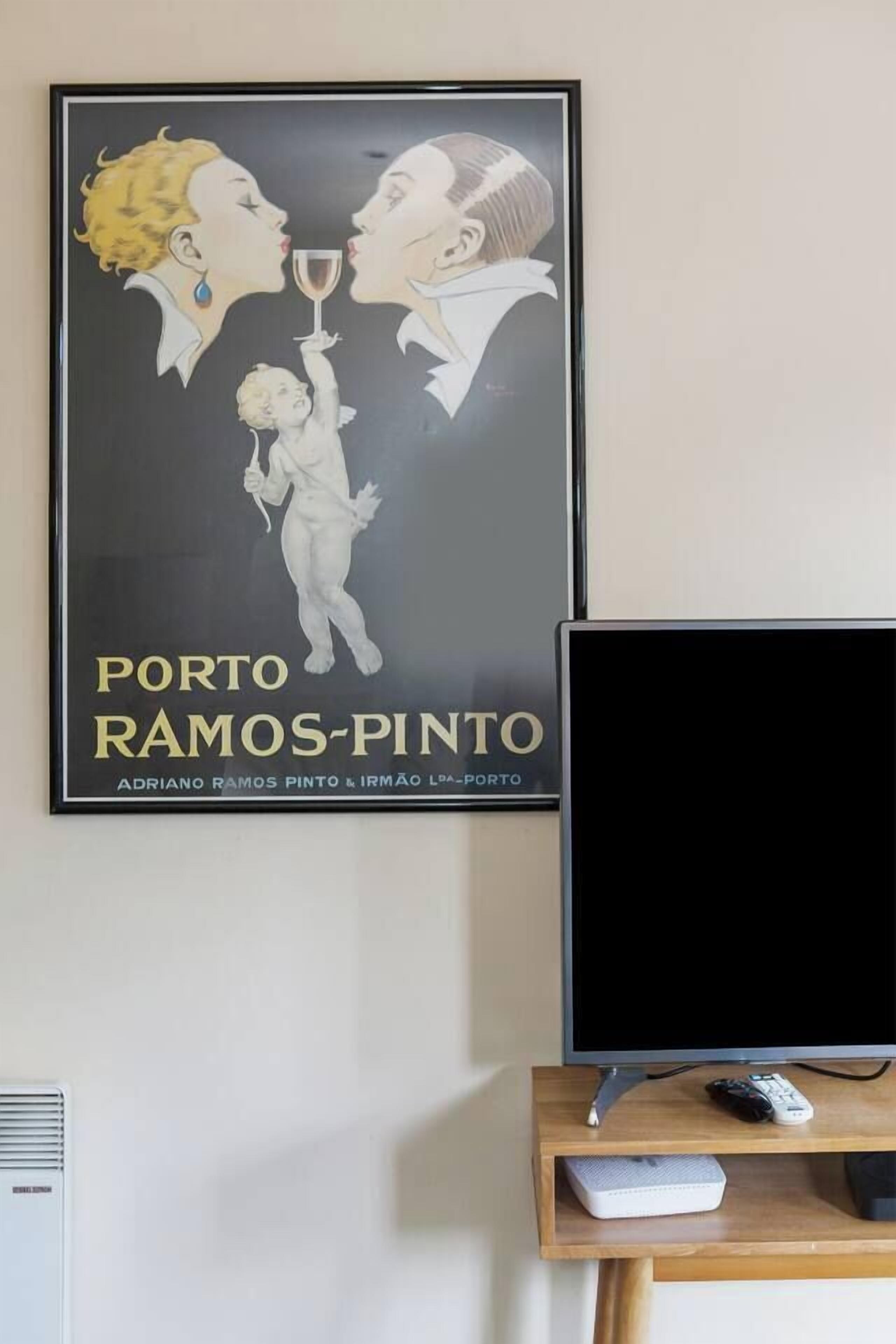Ein gerahmtes Kunstwerk mit dem Titel 'PORTO RAMOS-PINTO' von Adriano Ramos Pinto & Irmao Lda-Porto, ein Fernseher und eine Fernbedienung auf einem Holzständer.