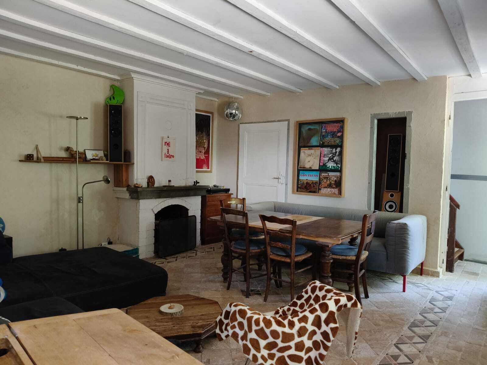 Ein Wohnzimmer mit Kamin, einem Esstisch mit Stühlen, einer Couch und einem Giraffen-Plüschtier.