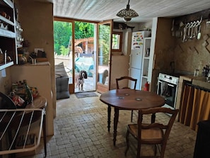 A kitchen with a dining table, chairs, a refrigerator, and a stove.