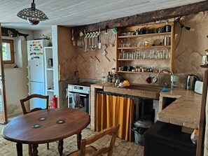 A compact kitchen with a stove, sink, and wooden shelves above.