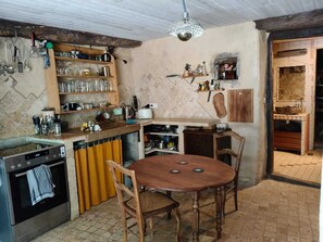 Cocina compacta con una mesa de comedor, sillas de madera, horno empotrado y una lámpara colgante.