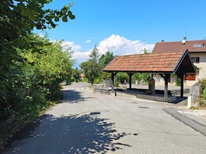 A quiet street with a covered shelter, a clear sky, and greenery on the sides.