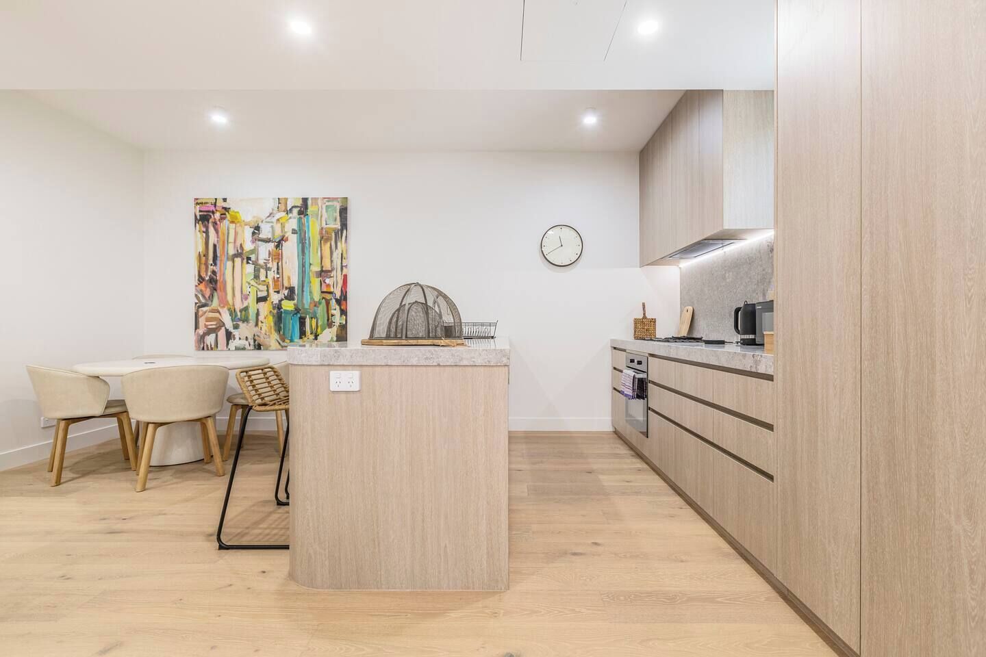 Une cuisine moderne dotée d’un îlot central, de meubles en bois et d’un coin repas avec des chaises.