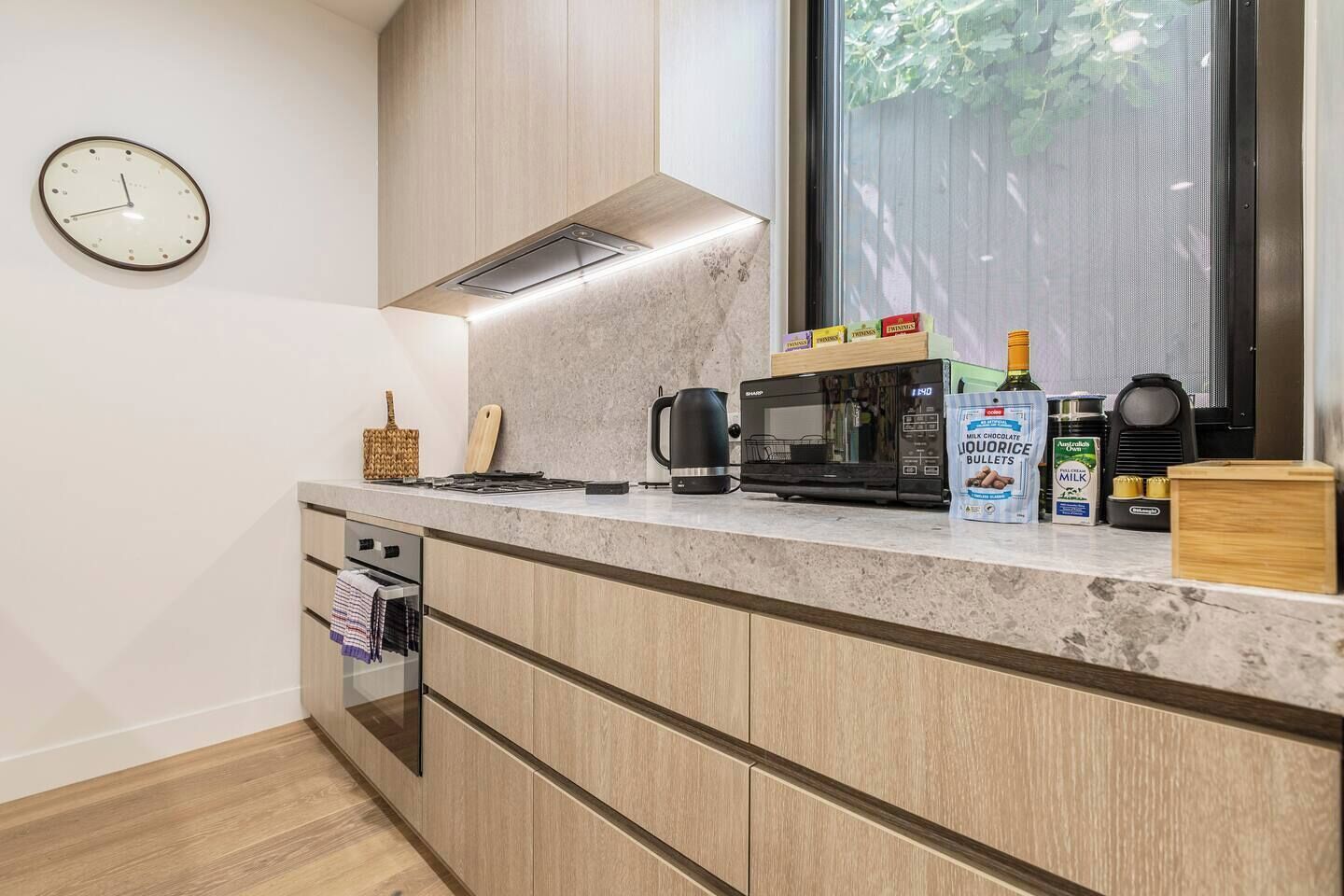 Una cocina moderna con microondas, cafetera y un paquete de bombones de chocolate con leche.
