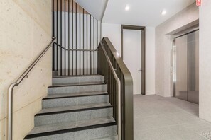 A staircase with metal handrails, a door, and an elevator in a modern building. - Alexandra Elegance Riverside Living in Style (South Yarra)