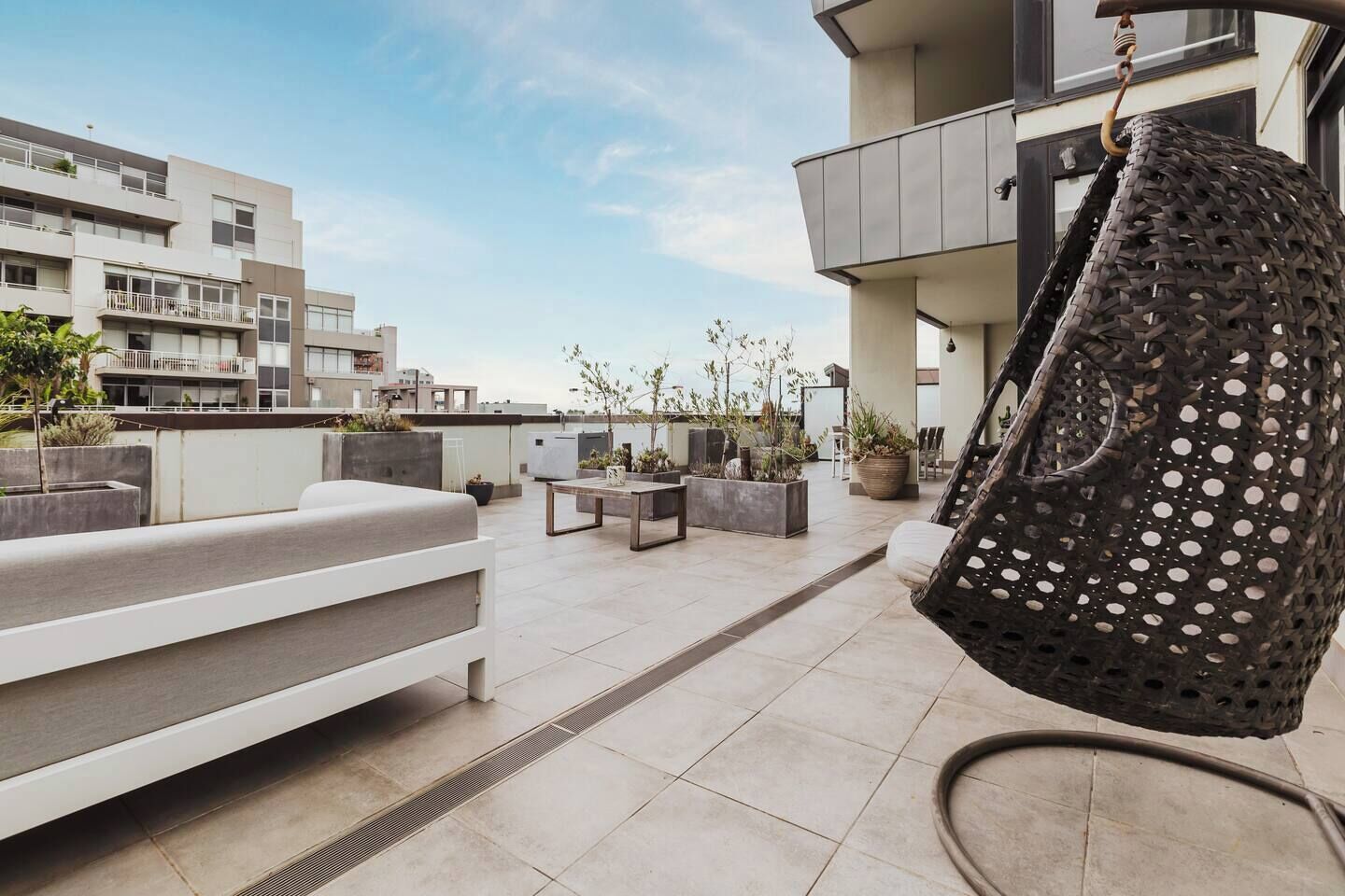 A rooftop terrace with outdoor seating, planters, and a hanging chair.