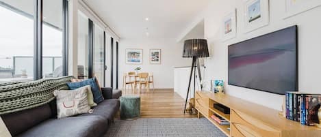 Uma sala de estar moderna com sofá, TV e estantes.