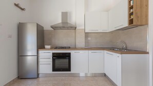 Eine moderne Küche mit Kühlschrank, Herd, Backofen und weißen Schränken.
