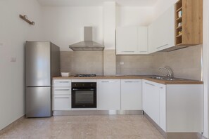 A modern kitchen with a refrigerator, stove, oven, and white cabinetry. - Attico Ilary by BarbarHouse (Gallipoli)