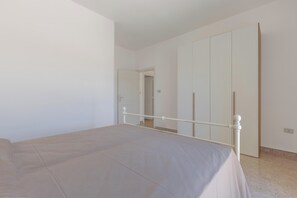 A bedroom with a bed, a wardrobe, and a door leading to another room. - Attico Ilary by BarbarHouse (Gallipoli)