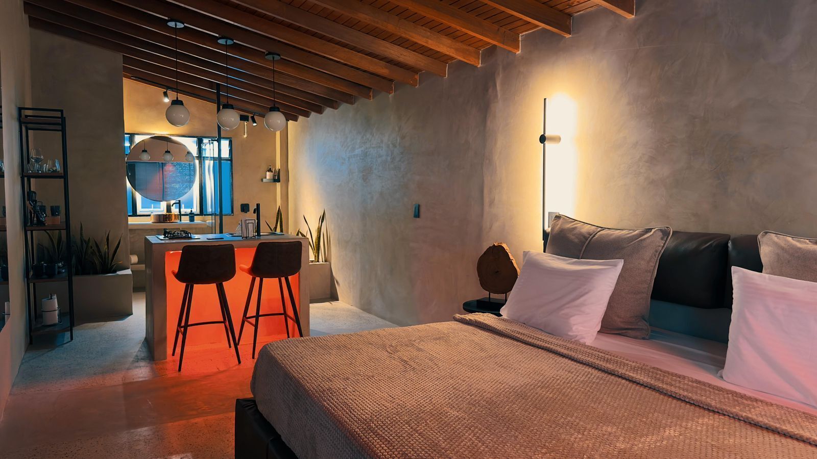 A modern bedroom with a large bed, a small desk area with two chairs, and a large window.