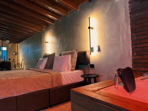 A bedroom with a bed, bedside tables, a nightstand, and a wooden headboard. - Luxury suit urban (Medellín)