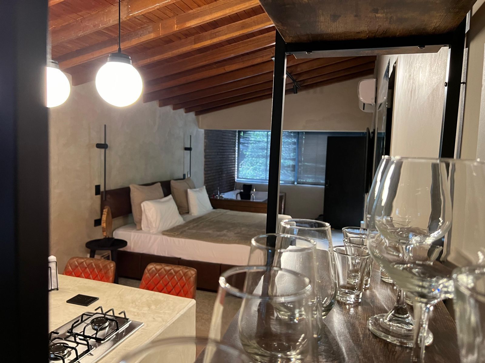 Ein modernes Interieur mit Küchenzeile, Esstisch und einem Schlafzimmer mit großem Bett und Fenster.