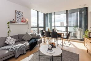 A modern living room with a sofa, coffee table, and dining area. - Coveted Collingwood Balcony Hideaway with Views (Collingwood)