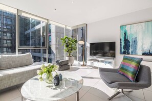 Uma sala de estar moderna com sofá, poltrona, mesa de centro e televisão.