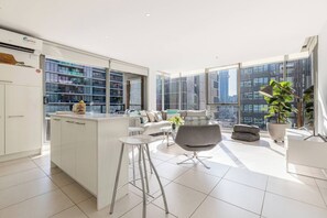 Un appartamento moderno con cucina, zona giorno e ampie finestre che offrono vista sulla città.