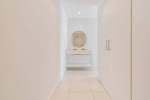Uma casa de banho moderna com uma toucador branco, um espelho redondo e um armário.