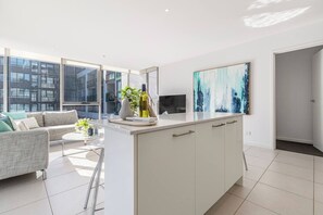 Um apartamento moderno com uma ilha na cozinha, um sofá e uma janela grande.