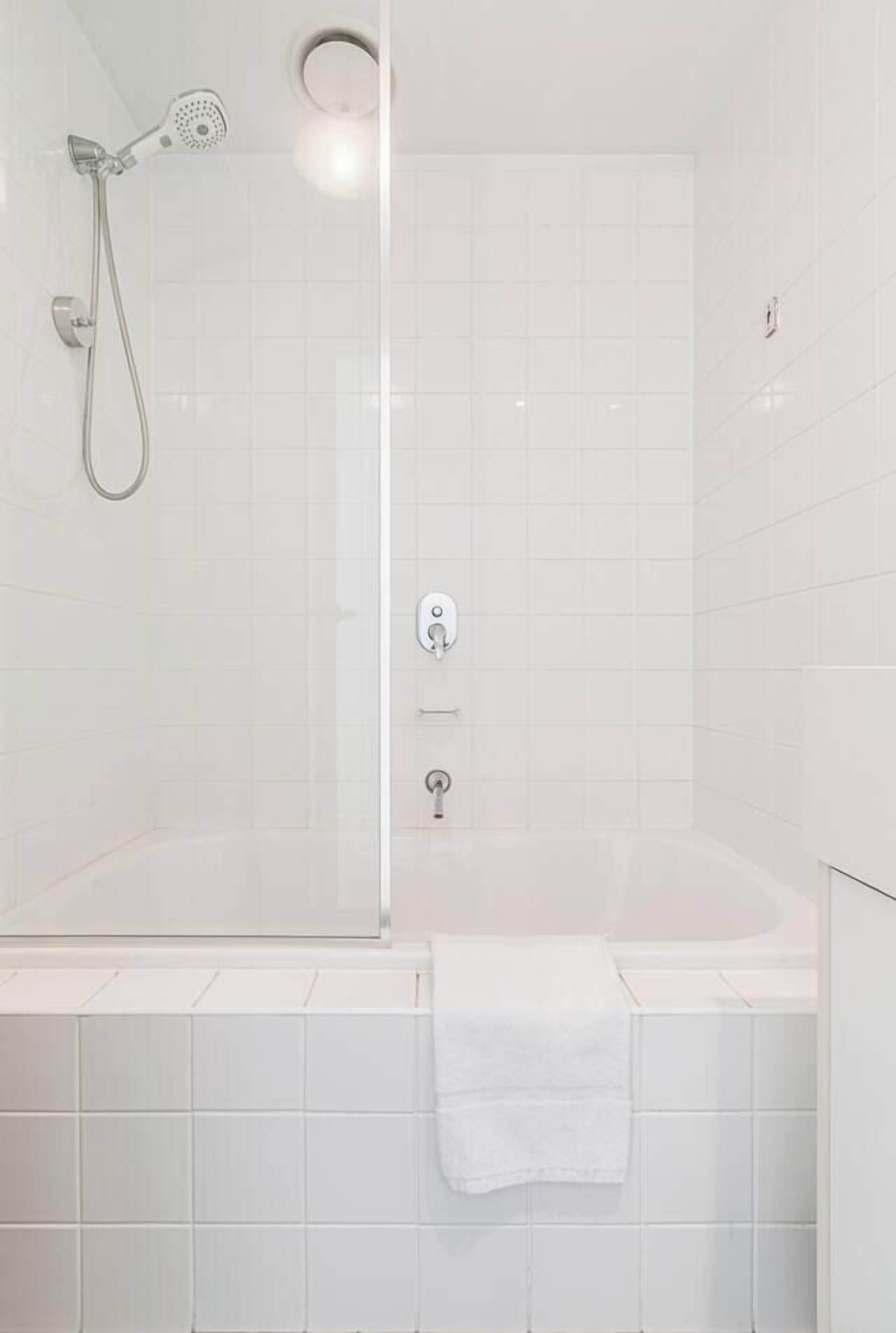 Ein modernes Badezimmer mit einer gläsernen Duschkabine, einer weißen Badewanne und einem Handtuch an der Wand.