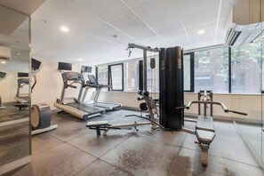 Ein Fitnessstudio mit Laufbändern, Kraftgeräten und einer Spiegelwand.