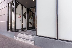 A building entrance with glass doors, a fire alarm, and a staircase leading to the entrance. - Cityscape Retreat Modern Comfort near Yarra River (Southbank)